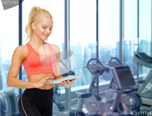 Image of smiling sporty woman with tablet pc in gym