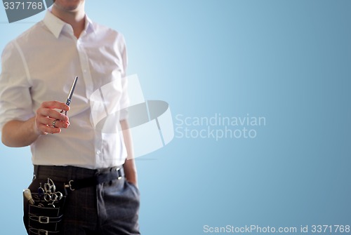 Image of close up of male stylist with scissors over blue