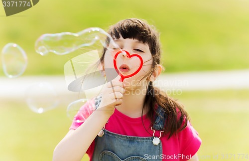 Image of little girl blowing soap bubbles outdoors