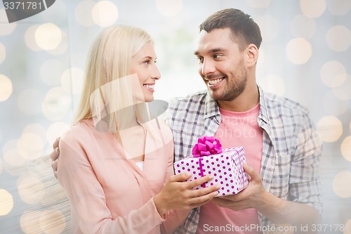 Image of happy man giving woman gift box over lights