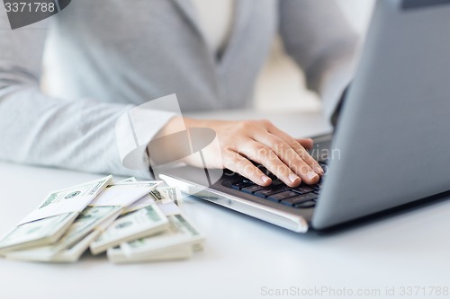 Image of close up of woman hands with laptop and money