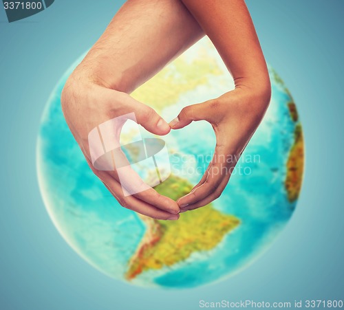 Image of human hands showing heart shape over earth globe