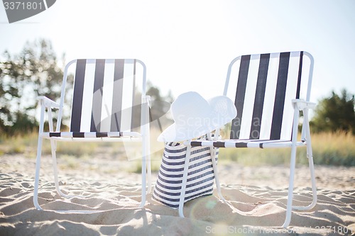 Image of two beach lounges with beach bag and white hat