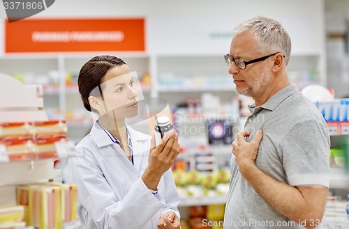 Image of pharmacist showing drug to senior man at pharmacy