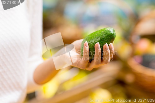 Image of close up of woman hand holding avocado in market