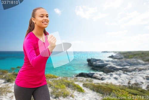 Image of smiling woman running on beach