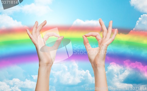 Image of hands showing ok sign over rainbow background