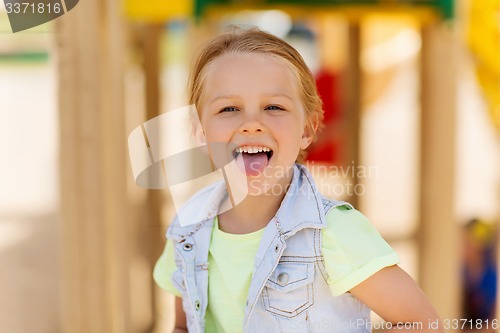 Image of happy little girl showing tongue on playground