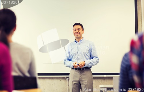 Image of group of students and smiling teacher in classroom