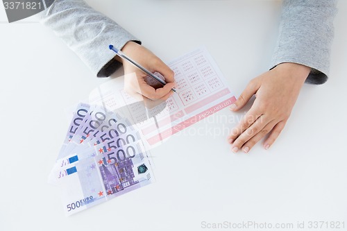 Image of close up of hands with lottery ticket and money