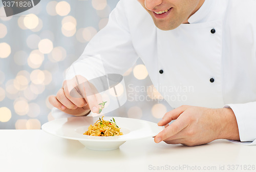 Image of close up of happy male chef cook decorating dish