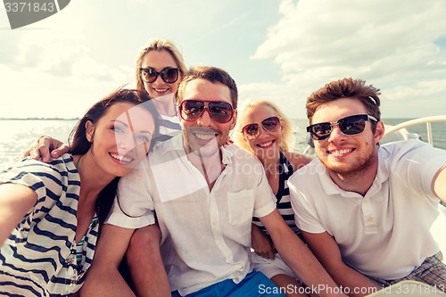 Image of smiling friends sitting on yacht deck