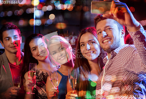 Image of friends taking selfie by smartphone in night club