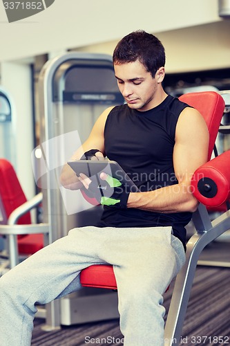 Image of young man with tablet pc computer in gym