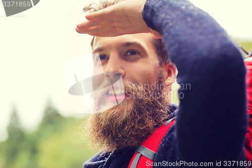 Image of smiling man with beard and backpack hiking