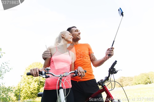 Image of couple with bicycle and smartphone selfie stick