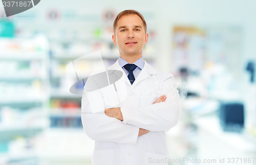 Image of smiling male pharmacist in white coat at drugstore