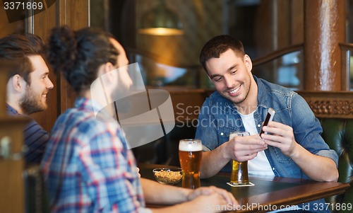 Image of male friends with smartphone drinking beer at bar