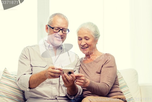 Image of happy senior couple with camera at home