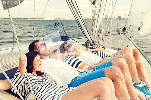 Image of smiling friends lying on yacht deck