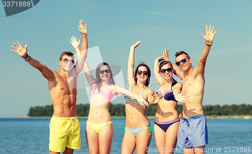 Image of smiling friends in sunglasses on summer beach