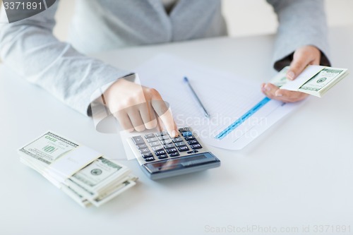 Image of close up of hands counting money with calculator