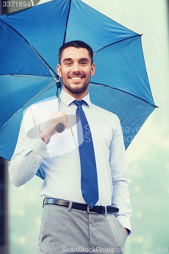 Image of young smiling businessman with umbrella outdoors
