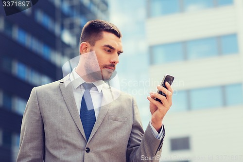 Image of serious businessman with smartphone outdoors