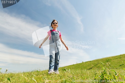 Image of happy little girl over green field and blue sky