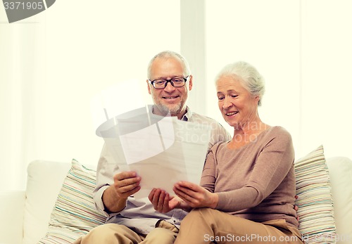 Image of happy senior couple with papers at home