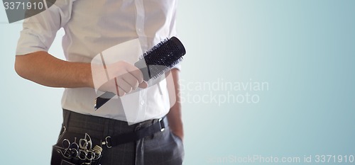 Image of close up of male stylist with brush at salon