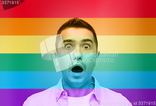 Image of shocked gay man shouting over rainbow flag