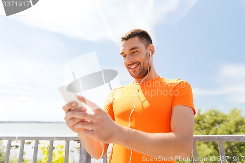 Image of smiling young man with smartphone and earphones