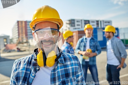Image of smiling builder with hardhat and headphones
