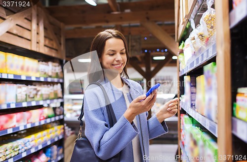 Image of happy young woman with smartphone in market