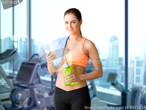 Image of smiling sporty woman with smartphone in gym