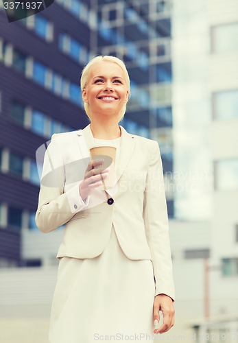 Image of smiling businesswoman with paper cup outdoors