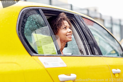 Image of happy african american woman driving in taxi