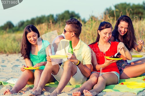 Image of smiling friends sitting on summer beach