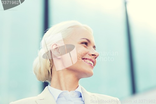 Image of young smiling businesswoman over office building