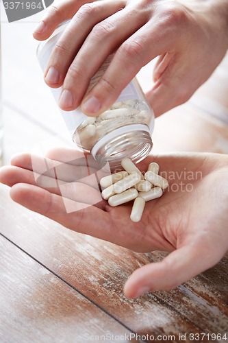 Image of close up of man pouring pills from jar to hand