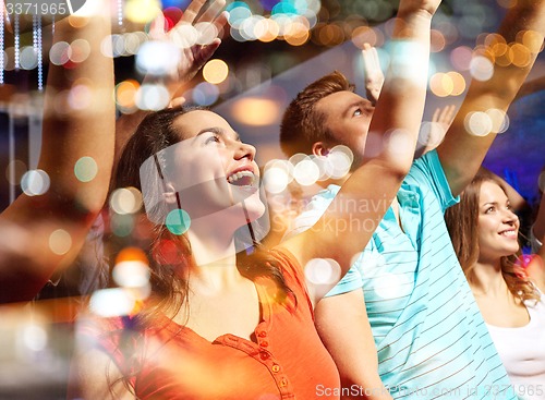 Image of smiling friends at concert in club