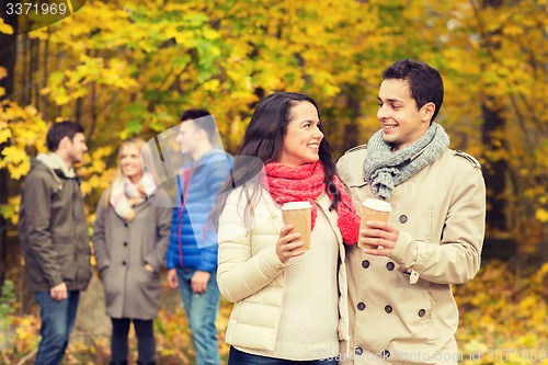 Image of group of smiling friend with coffee cups in park