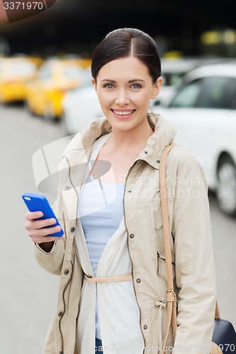 Image of smiling woman with smartphone over taxi in city