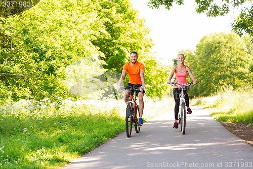 Image of happy couple riding bicycle outdoors