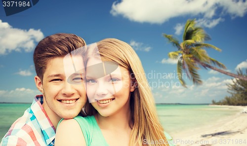 Image of smiling couple hugging over beach background