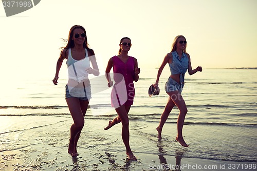 Image of group of smiling women running on beach