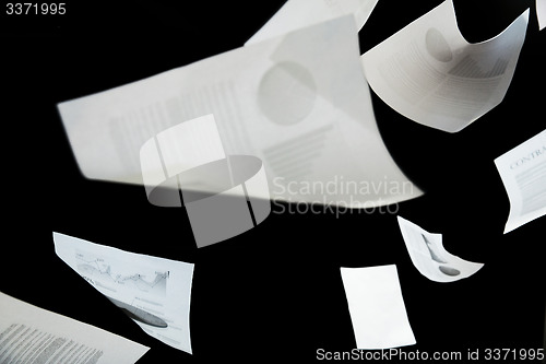 Image of business papers falling down over black background