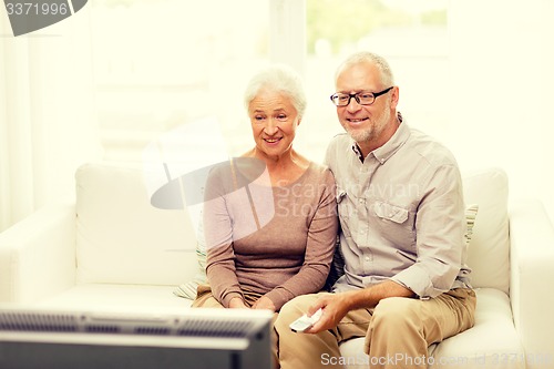 Image of happy senior couple watching tv at home