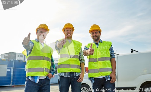 Image of happy male builders in high visible vests outdoors